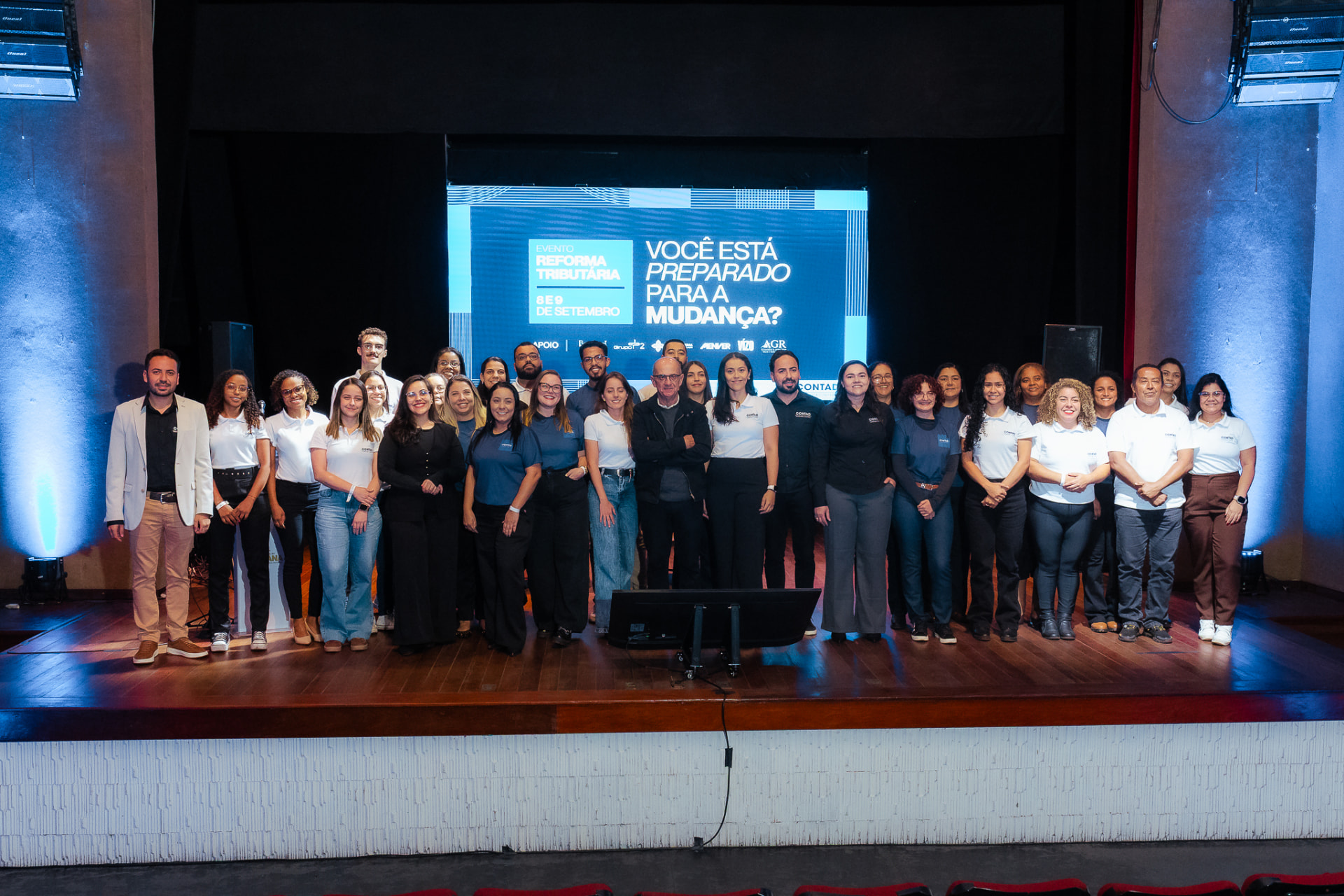 Participantes e equipe celebrando o encerramento do evento no palco